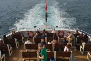 International guests watching the mangrove creeks from the open deck of a Tour De Sundarbans safari boat in the Sundarbans